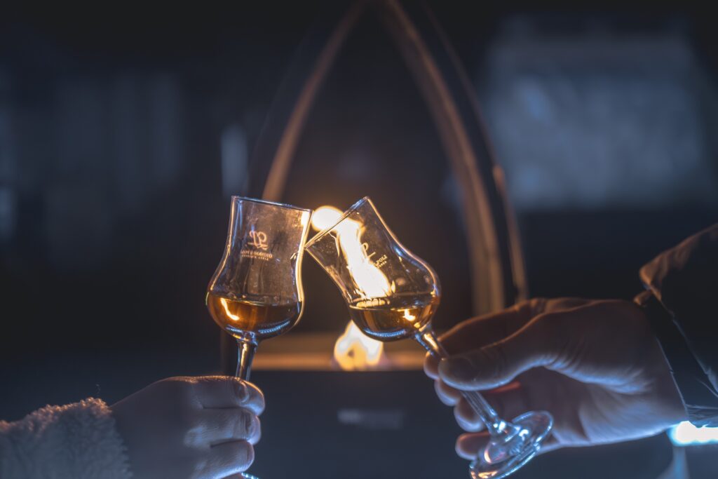 Due bicchieri di distillato che brindano davanti a un fuoco